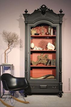 a black chair sitting in front of a tall book shelf filled with books and knick knacks