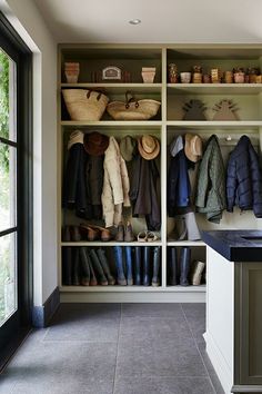 a walk in closet filled with lots of coats and shoes next to an open window