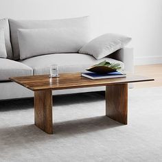 a coffee table sitting on top of a white rug in front of a gray couch