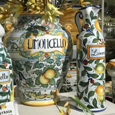 three large vases sitting on top of a table next to each other with fruit painted on them