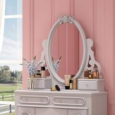 a white dresser sitting next to a pink wall with a mirror on top of it