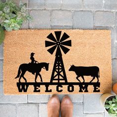 a door mat with the words welcome on it and two cows standing in front of a windmill