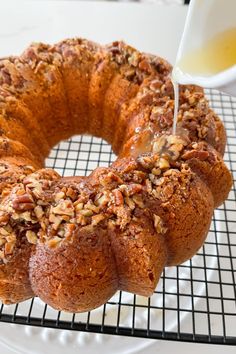 a bundt cake is being drizzled with icing on a cooling rack