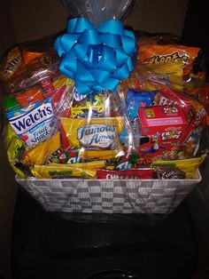 a basket filled with candy and candies wrapped in blue ribbon on top of a table