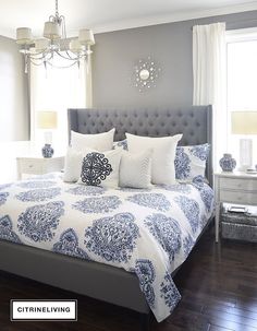 a large bed with blue and white comforters in a gray room next to a window