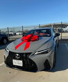 a gray sports car with a red bow on it's hood parked in a parking lot