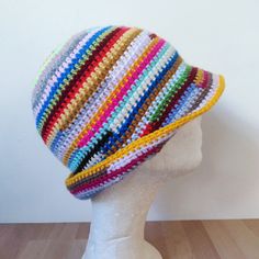 a white mannequin head wearing a multicolored crochet knit hat