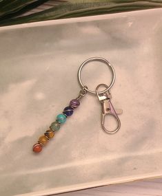 a keychain with seven chakra beads hanging from it's side on a white tray