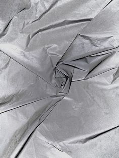 an up close view of a shiny silver material with some folds in the middle,