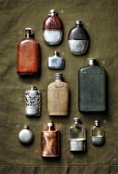 an assortment of different types of perfume bottles on a green cloth with labels in the middle