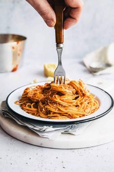 someone is holding a fork over spaghetti on a plate