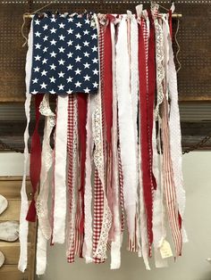 an american flag hanging on a wall with laces and ribbons attached to the strings