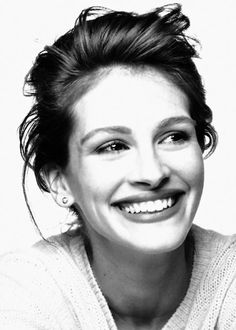 a black and white photo of a smiling woman with her hair in a top knot