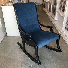 a blue rocking chair sitting on top of a cement floor next to a white counter