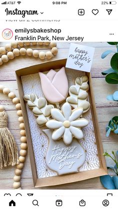 a box with some cookies in it on a table next to flowers and tassels