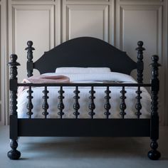 a bed with black headboard and foot board in front of white wall paneling