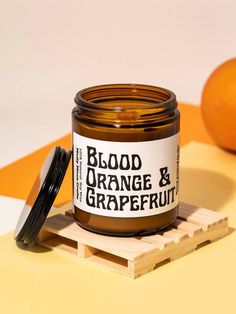 a jar of orange and grapefruit sits on a table next to an orange