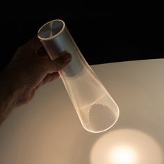 a person is holding a plastic tube in their hand on a white surface with a light shining through it