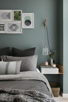 a bedroom with grey walls and pictures on the wall above the bed, along with pillows