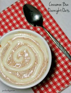 a bowl of cinnamon buns with cream in it on a red and white checkered tablecloth