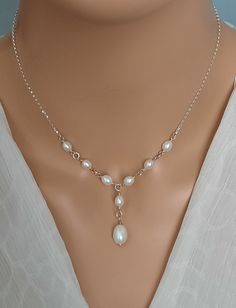 a woman wearing a necklace with pearls on it