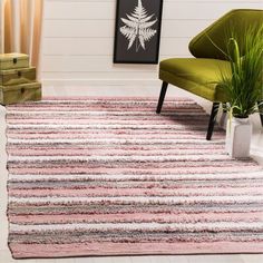 a living room area with a rug, chair and potted plant on the floor