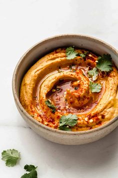 a bowl filled with hummus and garnished with cilantro