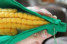 a hand holding a corn cob in a green bag with yellow kernels on it