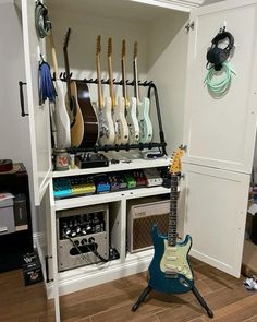 an electric guitar sits in front of a shelf with guitars on it and other musical equipment