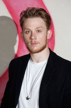 a man with a beard standing in front of a wall