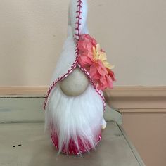 a white and pink stuffed animal with flowers on it's head sitting on a table