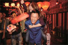 a group of people standing around each other in a room with lanterns on the ceiling