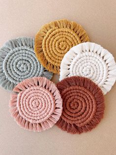 four woven coasters in various colors and sizes on a beige background with white fringe