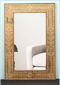 a white chair sitting in front of a mirror on top of a wooden table next to a potted plant