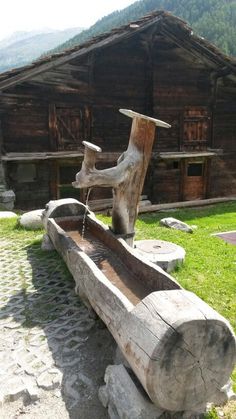 a wooden bench sitting on top of a grass covered field next to a log house