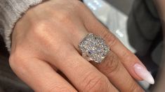 a woman's hand with a diamond ring on her finger and manicured nails