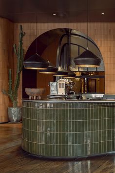 a kitchen with green tile and cactus in the corner, along with two hanging lights