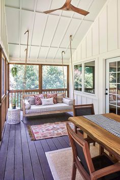 a porch with wood floors and white walls, wooden furniture on the front porch swing