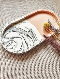 a marbled tray with dried flowers on the side and an oval shaped serving platter