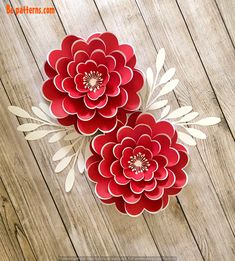 two paper flowers sitting on top of a wooden table