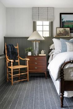 a bedroom with a bed, two chairs and a lamp on the nightstand in front of it