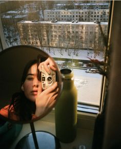 a woman taking a selfie in front of a window with a view of the city