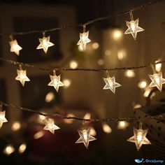 some white lights are hanging from a string with stars on them in the dark room