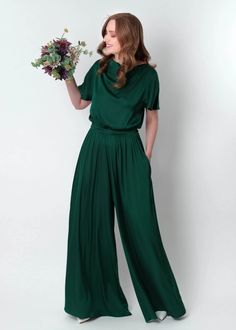 a woman in a green jumpsuit holding flowers