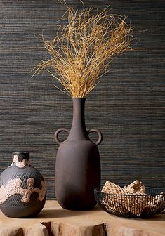 three vases with dry grass in them on a table next to a stone slab