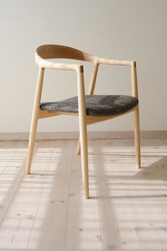 a wooden chair sitting on top of a hard wood floor next to a white wall