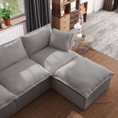 a large gray couch sitting on top of a rug in a living room next to a window