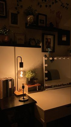 a desk with a lamp, mirror and books on it in a room that is dimly lit