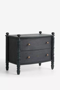 a black dresser with two drawers and gold knobs on the top, against a white background