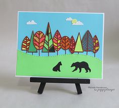 a card with an image of trees and two bears on the grass in front of them